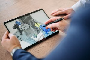 Mitarbeiter arbeitet mit Stift auf einem Tablet an einer technischen Planung