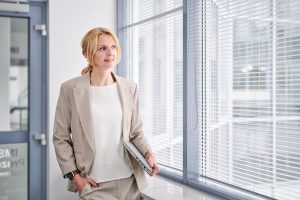 BBusinessportrait einer Geschäftsfrau mit Laptop am Bürofenster, Unternehmensfotografie Köln