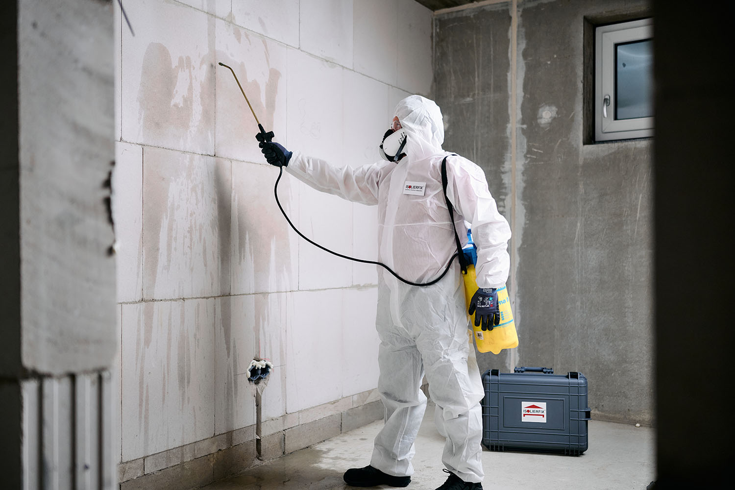Ein Handwerker in einem Schutzanzug sprüht eine Wand ein