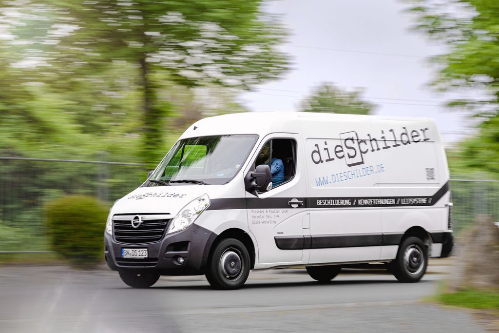 Ein Sprinter mit der Aufschrift "die Schilder" fährt vor Bäumen