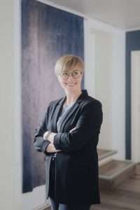 Mitarbeiterfoto einer Frau mit Brille im schwarzen Blazer