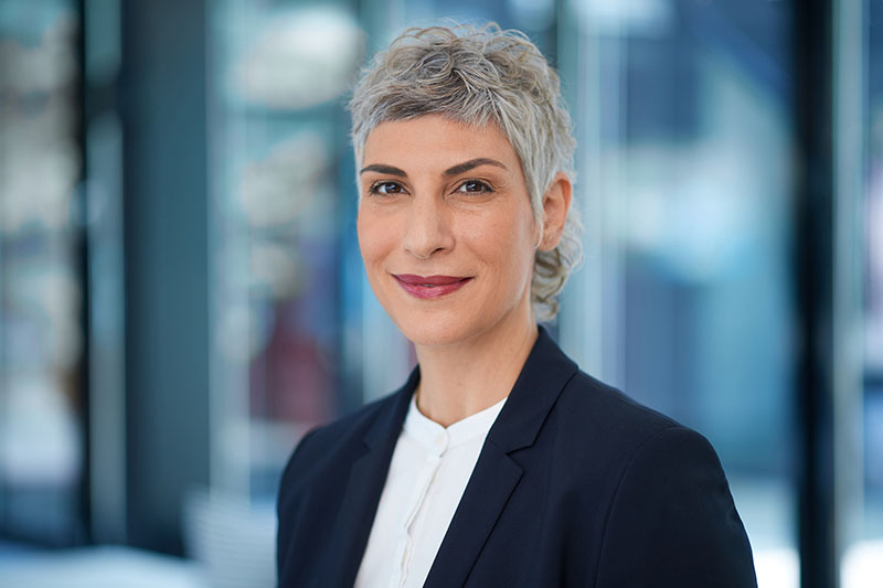 Professionelles Mitarbeiterfoto einer Frau im Business-Outfit in einem modernen Gebäude