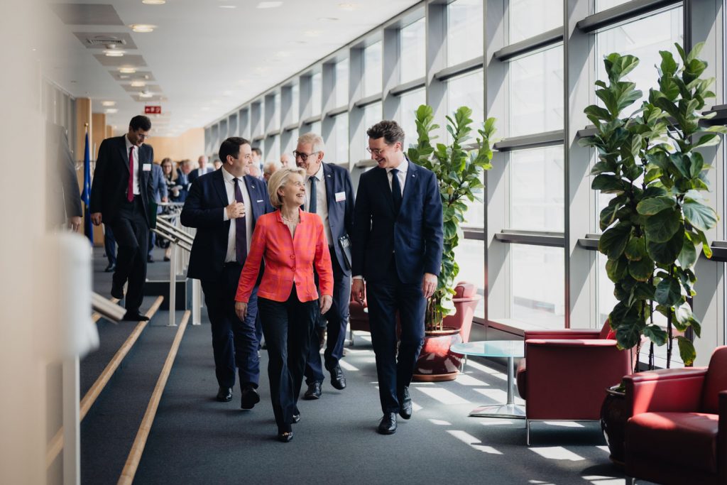 EU-Kommissionspräsidentin Ursula von der Leyen und NRW-Ministerpräsident Hendrik Wüst gehen durch einen hellen Flur und unterhalten sich.