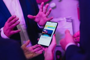 Zwei Personen zeigen eine App auf einem Smartphone bei einer Konferenz.