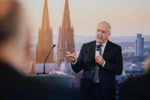Redner mit Mikrofon bei einer Konferenz in Köln, Kölner Dom auf der Hintergrundprojektion